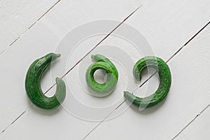 Misshapen cucumbers on white wooden table, top view