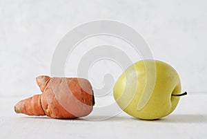 Misshapen golden apple and carrot on white photo