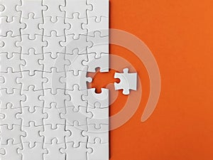 Missing piece of the puzzle, white puzzle pieces on orange background