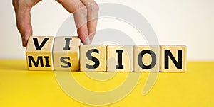 Mission vision symbol. Businessman hand turns wooden cubes and changes the word `mission` to `vision`. Beautiful yellow table,