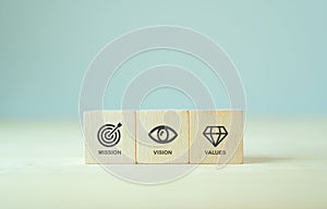 Mission, vision and values of company. Purpose business concept. The wooden cubes with mission, vision and values symbols on grey