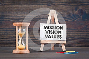 Mission, Vision and Values. Sandglass, hourglass or egg timer on wooden table photo