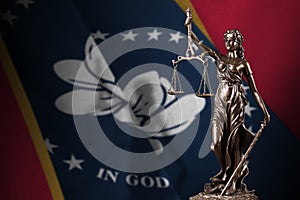 Mississippi new US state flag with statue of lady justice and judicial scales in dark room. Concept of judgement and