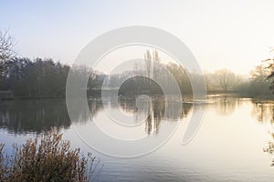 Mist across a lake thins as the rising sun warms up the land