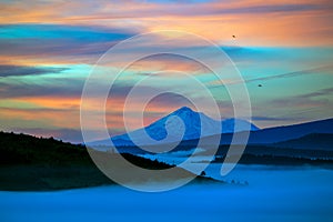 Mist-clad vegetation and mountain range during the beautiful sunrise