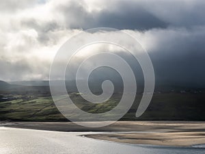Mist-covered hills in the Scottish highlands with beach and dramatic clouds, Sutherland, Scotland photo