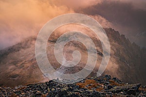 Mist and fog over the top of the hill in mountains evening orange light. autumn mood in hills