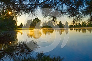 Mist over a tranquil lake at sunrise  with the orange glow