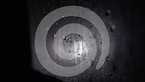 Misted car window with water drops at night