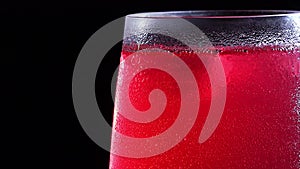 A misted glass with a drink and bubbles in close-up. Cold drink with ice