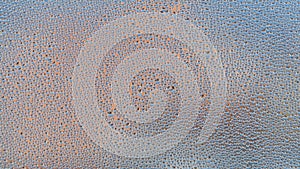 Misted glass of window with water drops texture and blurred buildings at the background.