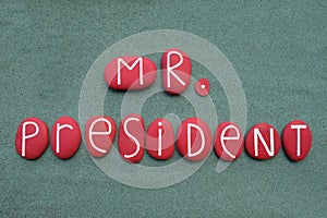 Mister President text composed with red colored stone letters over green sand