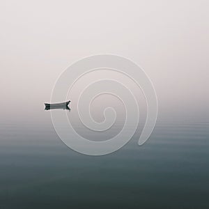 Mistic lonely boat in the middle of the lake, mist fog