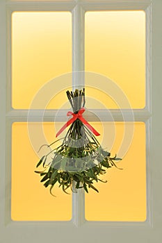 Mistletoe bunch with red bow hanging on window. Traditional Christmas decor