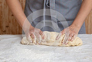 Mistress kneads the dough in the kitchen