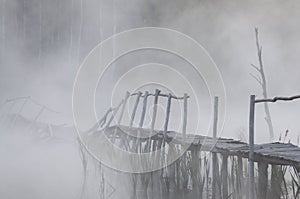 Misty bridge on the foggy lake in the morning at dawn