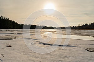 Misty calm evening on the forest lake is illuminated by the colors of sunset, melting ice, reflection in the water mirror