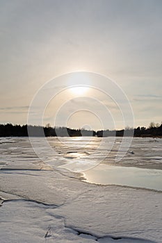 Misty calm evening on the forest lake is illuminated by the colors of sunset, melting ice, reflection in the water mirror