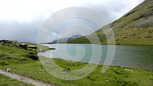 Misty cold morning after heavy rain at lake banks in Alpine mountains. Heavy dark clouds of mist