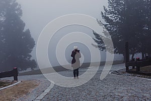 Misty fog landscape in a mountain. young woman taking pictures. winter or autumn concept
