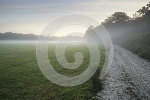 Misty landscape during sunrise in English countryside landscape