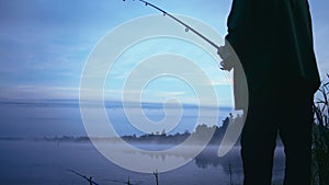 Misty Morning Catch: Fisherman Reeling in the Lake