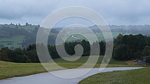 Misty morning in the countryside road with hills, forests, and fields in the background