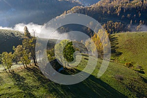 Misty morning in the mountains. Aerial drone view of abandoned hut and homestead