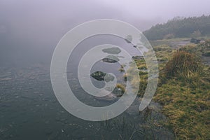 Mlhavé ráno pohled v mokré horské oblasti ve slovenských Tatrách. panorama horského jezera - vzhled vintage filmu