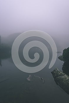 Mlhavé ráno pohled v mokré horské oblasti ve slovenských Tatrách. panorama horského jezera - vzhled vintage filmu