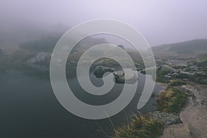 Misty morning view in wet mountain area in slovakian tatra. mountain lake panorama - vintage film look