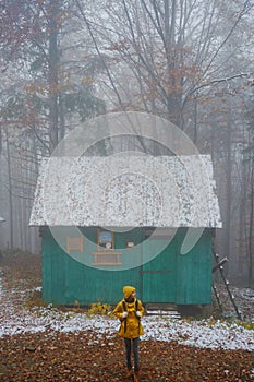 Misty morning in the woods, alone woman standing by old house, lost in foggy forest