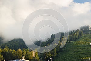 Misty mountain landscape with fir forest. Beautiful landscape with mountain view, cable car. Postcard view. Travel concept. Sunset