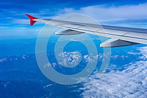 misty mountain peaks from the airplane flying above the alps with plane wing