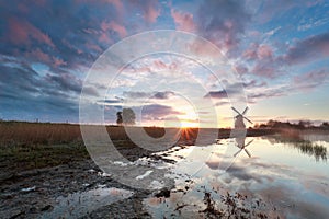 Misty sunrise behind Dutch windmill
