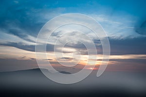 Misty sunrise clouds below mountains tree silhouette