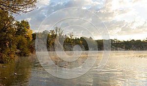 Misty sunrise over a lake. A foggy morning on autumn by a small lake. Misty reflection in water. Dreamy wanderlust, web photo