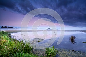 Misty sunrise over wild lake