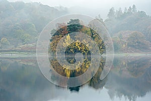 Misty tranquil reflections in autumn by Rydal water in the Lake District