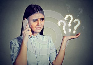 Misunderstanding. Upset woman talking on mobile phone has many questions photo