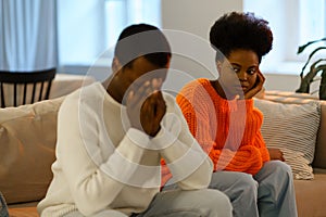 Misunderstandings in love relationships. Sad african family couple sitting on sofa after conflict