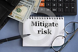 MITIGATE RISK - words in a notebook against the background of money, glasses and calculator