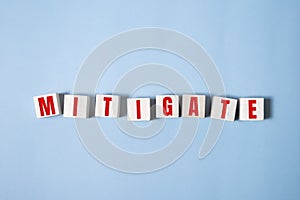 MITIGATE word made with building blocks on blue photo