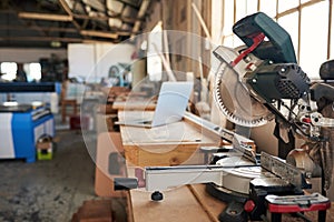 Mitre saw and laptop on workbenches in a woodworking shop