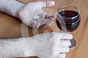 Mix alcohol with pills antibiotics red wine glass white hand table closeup concept combine