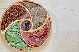 Mix of asian spices on the wooden plate: star anise, bay leaves, paprika, dried cloves and cumin close up. Spices background