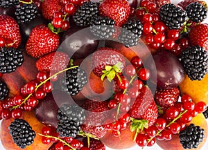 Mix berries and fruits on white background. Ripe blackberries, strawberries, red currants, plums and peaches. Top view. Background