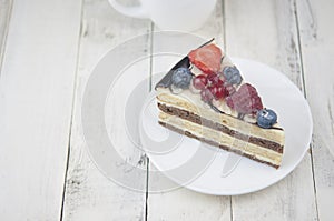 Mix berry cheese cake on white plate on wood background