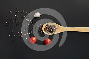 mix of black hot pepper, wooden bowl or spoon, black table or surfaces