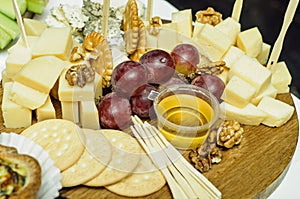 Mix cheese on wooden board with grapes. Front view.